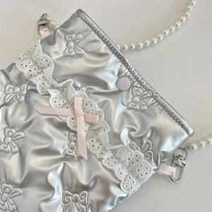 Dettaglio borsa trapuntata argento con pizzo, nastro rosa e catena di perle