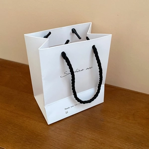 White paper gift bag with black handles for jewelry and luxury accessory packaging