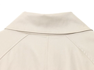Dettaglio del risvolto del trench beige che mostra il tessuto in twill e le cuciture