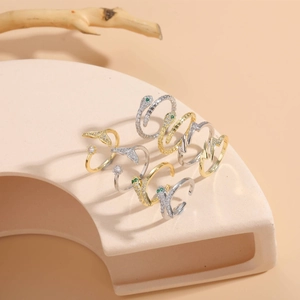 Detail of snake head and fish tail rings with green zircon stones on minimalist stand