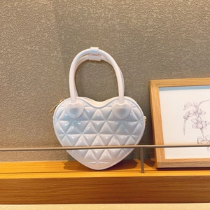 Detail of heart-shaped quilted handbag in pearl white with metallic zipper and top handles