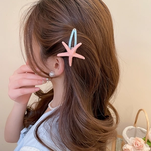 Detailed view of a pink starfish hair clip styled on wavy hair for a beach vacation look