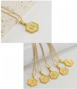 Detail of gold stainless steel hexagonal initial pendant with embossed letter and bead edge
