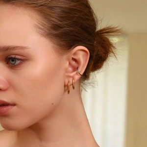 Detail showing combination of 18K gold hoop earrings and dark grey minimalist ear cuff