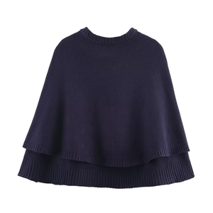 Detail of dark blue knitted poncho featuring a unique double-layer hem and round neck design