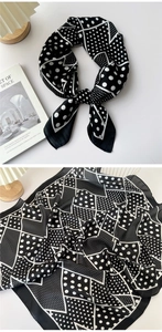 Detail of black and white silk scarf with polka dots and geometric patterns on a white desk
