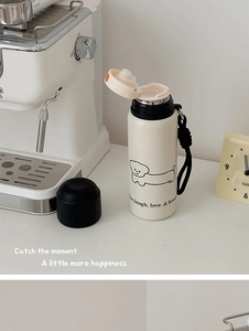 Detail of cream white insulated bottle with cartoon dog print and woven carry handle