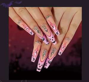 Detail of pink Halloween coffin press-on nails with flame, moon, and pumpkin rhinestone patterns