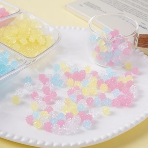 Mezcla de cuentas de estrella de resina de colores y caramelos falsos en plato blanco