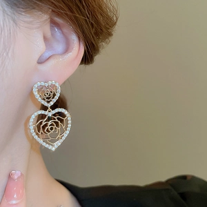 Dettaglio ravvicinato di orecchini a cuore in oro con zirconi indossati da una modella