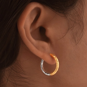 Two-tone gold and silver stainless steel hoop earrings with diamond pattern on model