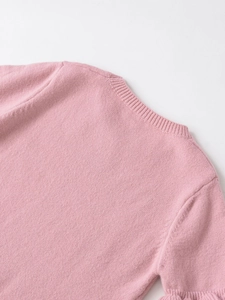 Detail of pink knitted sweater showing ribbed neckline and fine textured knit fabric