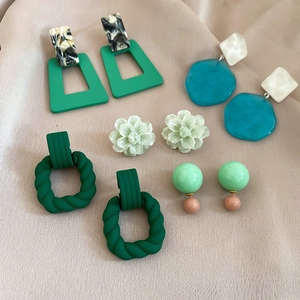 Detailed set of five assorted green and blue acrylic geometric drop earrings on silk