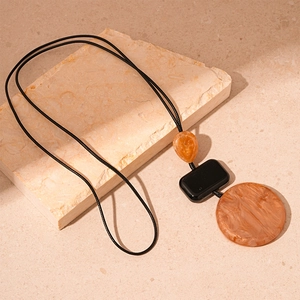Minimalist resin geometric necklace featuring amber and black pendants on a black cord
