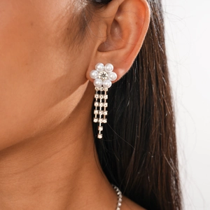 Detail shot of vintage pearl flower earrings with diamond tassels on a female model