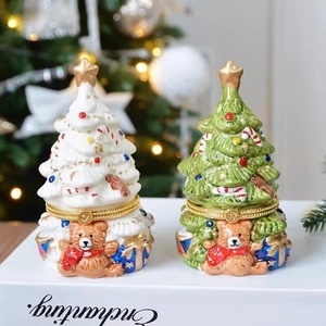 Close-up of white and green ceramic Christmas tree jewelry boxes with gold star details