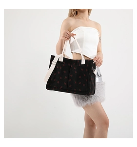 Detail of strawberry print corduroy tote bag featuring front pockets and adjustable strap