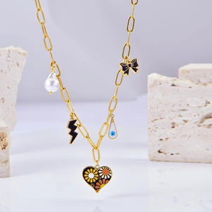 Collier cœur doré avec perle, nœud noir et breloques fleuries sur support pierre