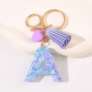 Detail of purple letter A resin keychain with heart sequins and leather tassel