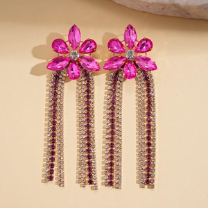 Détail de boucles d'oreilles fleurs roses avec longs glands en strass violets