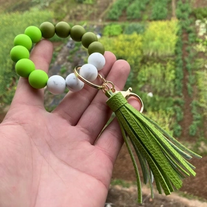 Macro detail of silicone beaded keychain with marble patterns and green leather tassel