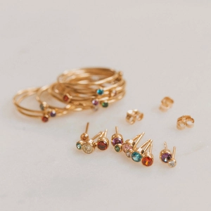 Set of gold stackable rings and colorful gemstone stud earrings for women in December