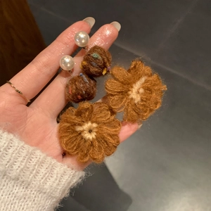 Detailed view of handmade crochet flower earrings with warm brown tones and pearls