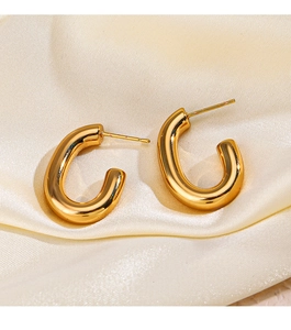 Macro detail of high-polished 18K gold-plated C-shape hoop earrings on silk fabric