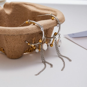 Detailed view of silver C-shape hoop earrings with gold beads and pearl chain tassels