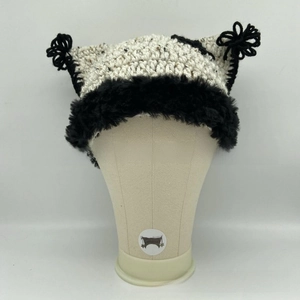 Detail of handmade knit cat ear beanie with black faux fur trim and pom-pom accents
