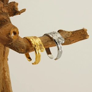 Artistic display of gold and silver liquid lava textured open rings on wooden branches