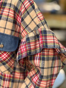 Détail des poignets à volants et poche en denim sur une chemise à carreaux en tissu tissé