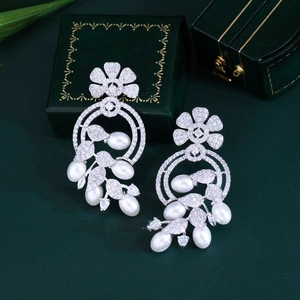 Macro shot of silver floral earrings with sparkling zircons and white teardrop pearls