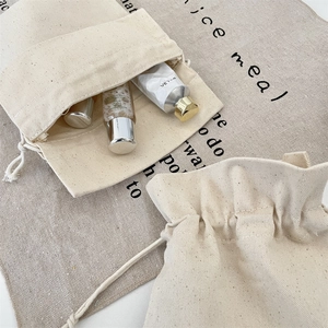 Detail of cream canvas drawstring bags showing thick twill texture and travel storage use