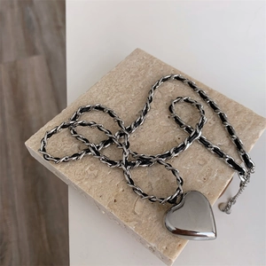 Close-up of titanium steel chain with black leather cord and 3D heart pendant