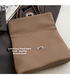 Close-up of brown striped tote bag with elegant silver twist lock and chain strap detail