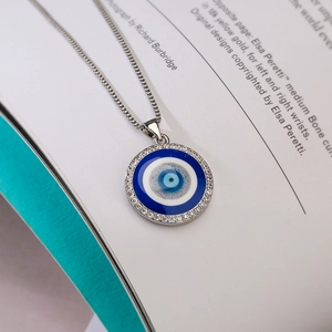 Macro shot of silver box chain necklace with blue zircon evil eye enamel pendant