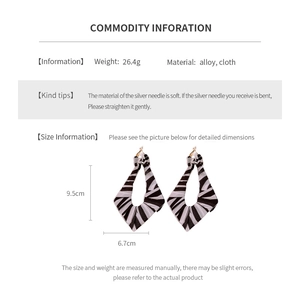 Macro detail of large zebra print fabric drop earrings with dimensions and weight info