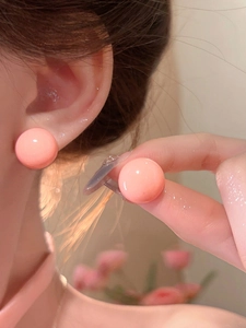 Close-up shot of glossy pink round stud earrings featuring a minimalist dopamine design