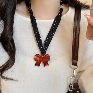 Close-up of vintage polka dot ribbon necklace with amber resin bow pendant on model