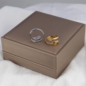 Detailed view of arrow-shaped open rings in gold and silver finish on a velvet box