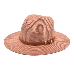 Detail of salmon pink straw panama hat with brown leather band and gold buckle
