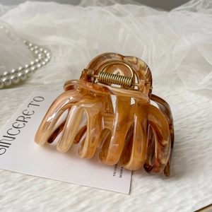 Macro detail of amber marble texture hair claw clip with golden metal spring
