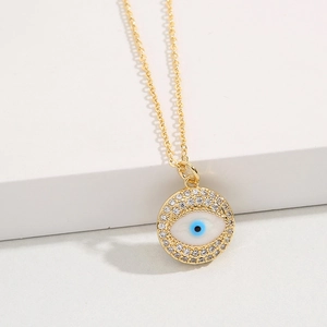 Golden Evil Eye pendant necklace with blue center and clear zircons on white pedestal