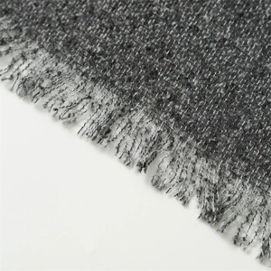 Macro detail of grey faux cashmere scarf featuring textured knit fibers and soft tassel edges