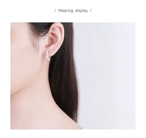 Wearing display of S925 silver hoop earrings featuring multiple white pearls on model