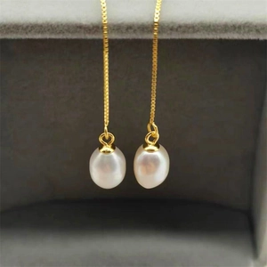 Macro detail of natural teardrop pearls and elegant long gold chain tassel earrings