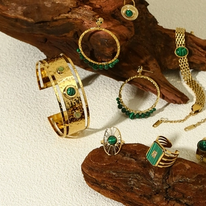 Detail of 18k gold jewelry set with green malachite stones on wood display