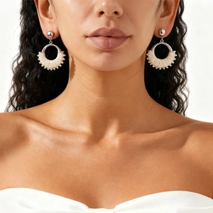 Close-up of white woven geometric round earrings with metal hooks on a female model