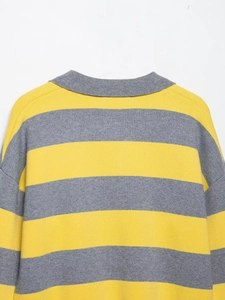 Détail du col polo gris et des rayures en maille dense sur le pull rayé jaune et gris